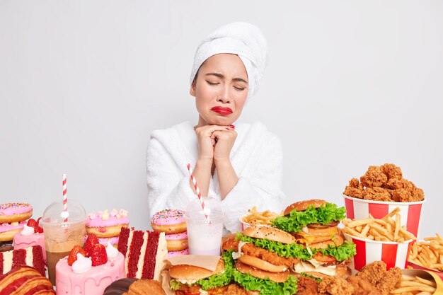 過食症の概念。ストレスのたまった不幸なアジアの女性はファーストフードを食べたい