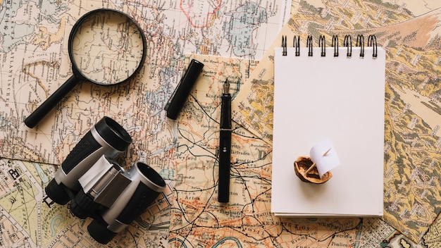 Binoculars and magnifying glass near pen and notebook