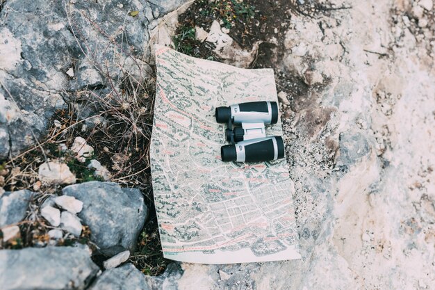 Binoculars and map on rock