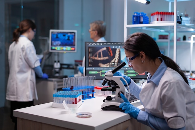実験室で顕微鏡上でウイルスの反応を研究している生化学者の科学者