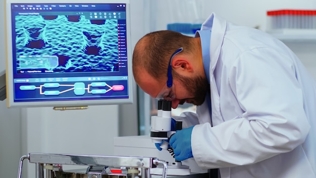 제약 실험실에서 새로운 백신에 대한 연구를 하는 현미경을 사용하는 생물학 기술 과학자. covid19에 대한 진단을 연구하는 첨단 기술을 사용하여 바이러스 진화를 조사하는 동료