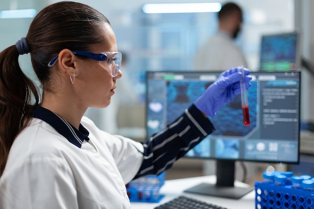 Биолог-исследователь держит пробирку для анализа крови, анализируя медицинскую экспертизу ДНК