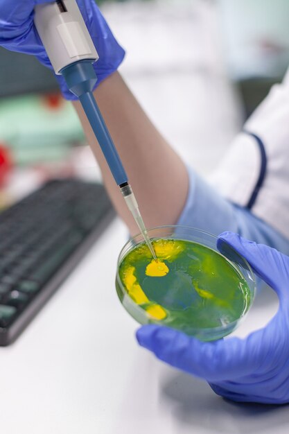 Biologist researcher using micropipette and petri dish