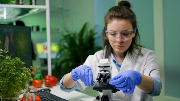 Biologist taking green leaf sample putting under microscope