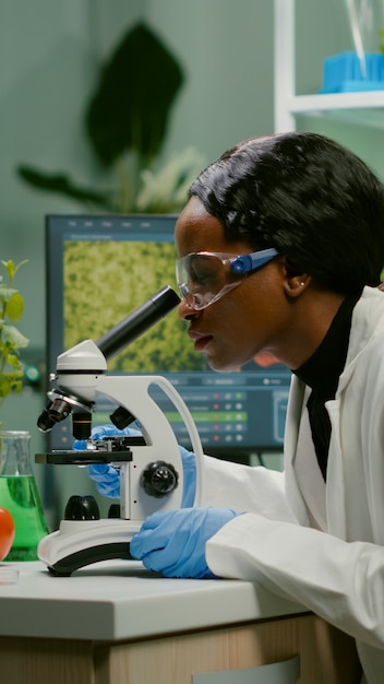 顕微鏡を使用して医学的専門知識のために生物学的スライドを調べる生物学者の女性