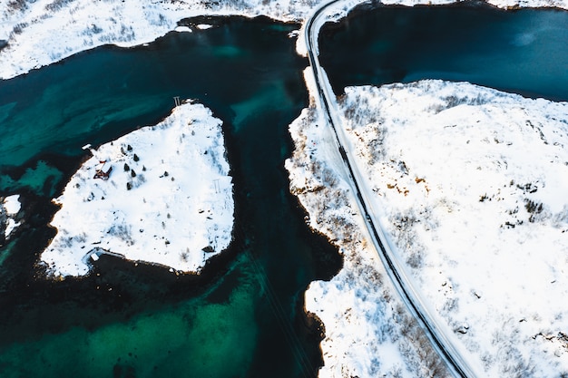 Foto gratuita colpo dall'alto di una strada che attraversa isole innevate su uno specchio d'acqua