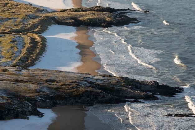 Бесплатное фото Вид с высоты птичьего полета на волны, разбивающиеся о пляж со скалами на берегу