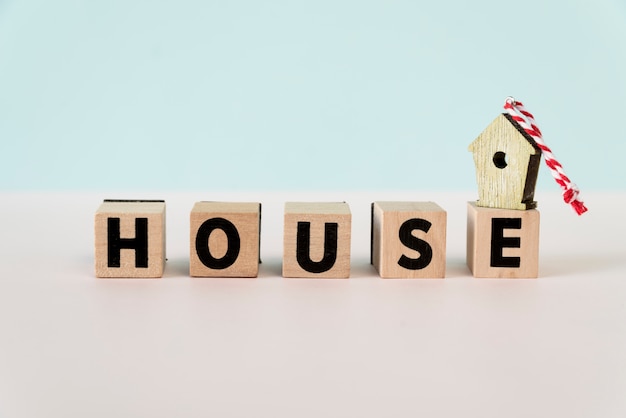 Birdhouse ornaments on wooden house block against blue backdrop