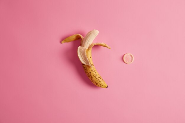 Birth control, safe relationship concept. Peeled ripe banana and condom. View from above.