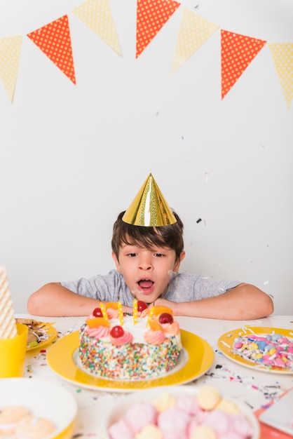 誕生日の男の子がケーキの上のろうそくを吹き