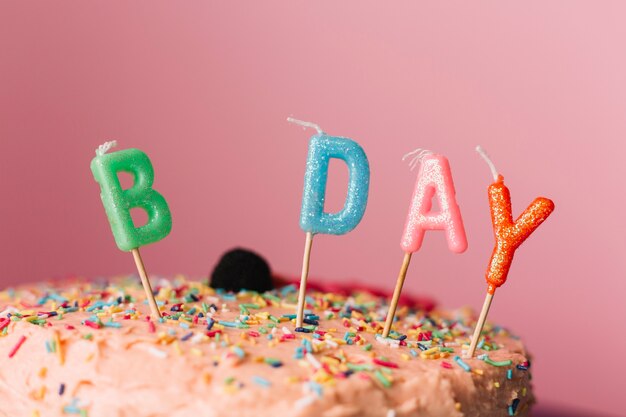 Birthday candles on cake against colored background