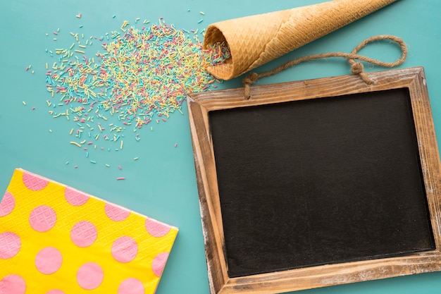 Free photo birthday composition with slate, ice cream cone and napkins