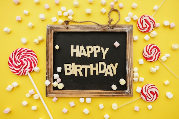 Free photo birthday composition with slate, marshmallows and lollipops