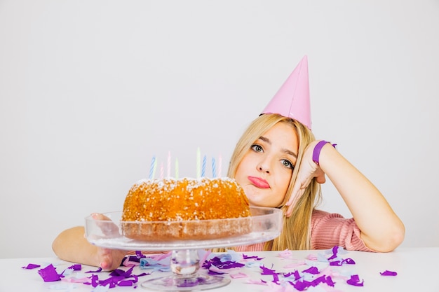 Birthday concept with bored girl behind cake