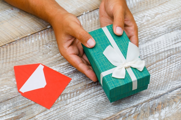 Birthday concept with card in envelope on wooden background high angle view. man passing gift box.