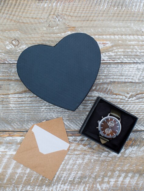 Birthday concept with envelope, gift boxes with watch on wooden background flat lay.