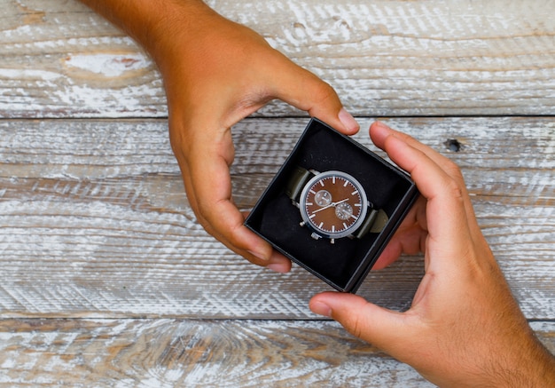 Concetto di compleanno sulla disposizione piana del fondo di legno. lancette che danno e ricevono scatola per orologi.