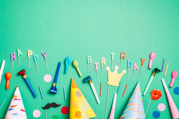 Foto gratuita sfondo di festa di compleanno con cappelli da festa; puntelli; palloncini; soffiatore di corno e candele su sfondo verde