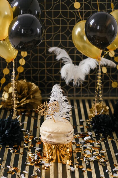 Праздничный торт с золотым и черным декоративными шарами.