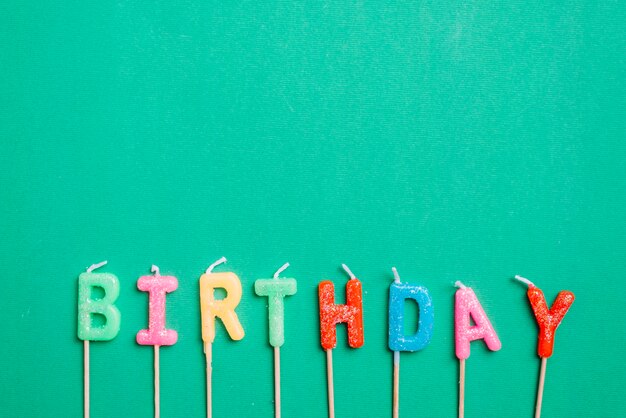 Birthday text candles with stick on green background