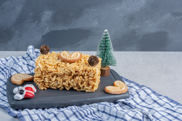 Biscuit cake with flaky cookies and christmas ornaments on a board on marble surface