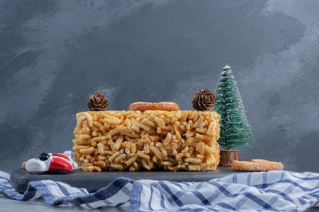 Biscuit cake with flaky cookies and christmas ornaments on a board on marble surface