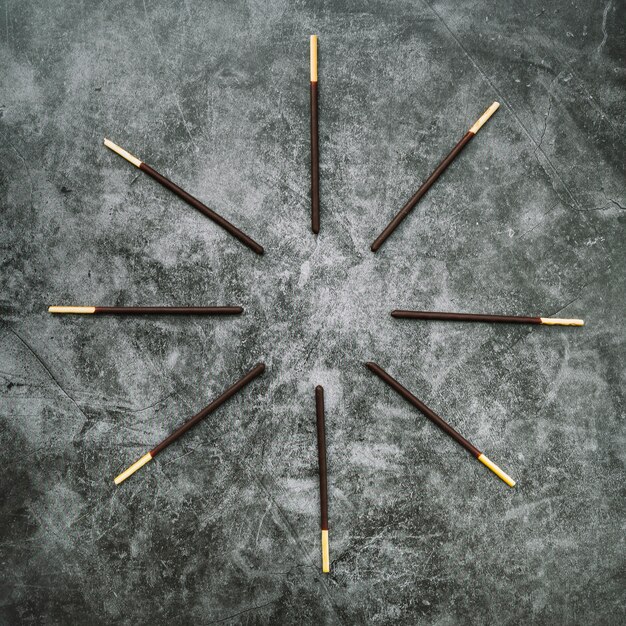 Biscuit stick deep in chocolate arranged in circular on stained concrete background