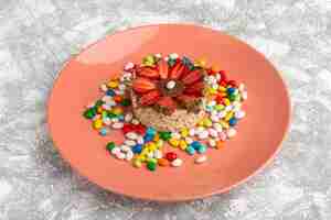 Free photo biscuit with strawberries inside peach plate along with candies