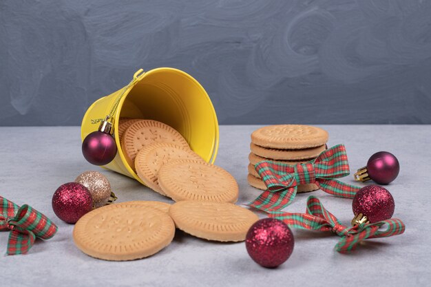 Biscuits in bucket decorated with ribbon and Christmas balls on white table. High quality photo