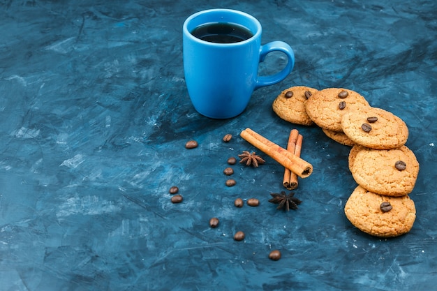 Foto gratuita biscotti e tazza di caffè su uno sfondo blu scuro
