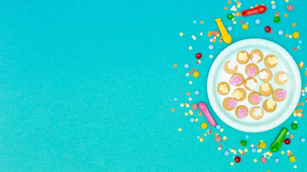 Тарелка с печеньем в окружении воздушных шаров и конфетти