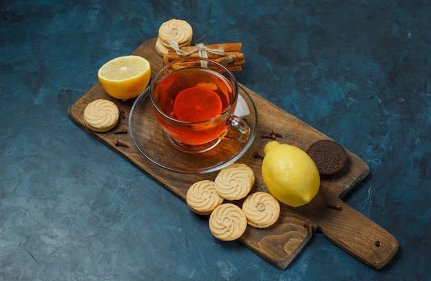 Biscotti con spezie, tè, limone su blu scuro e tagliere