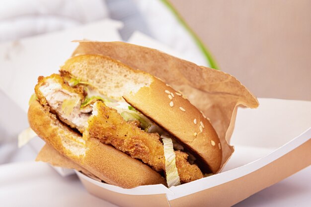 Bitten burger in a cardboard box, close up.