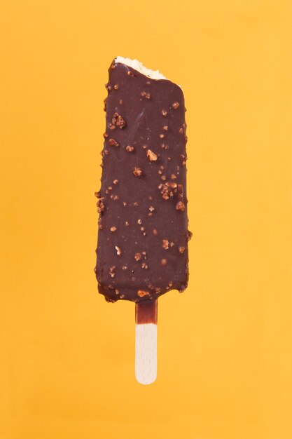 Bitten dark chocolate almond ice cream on a yellow orange background