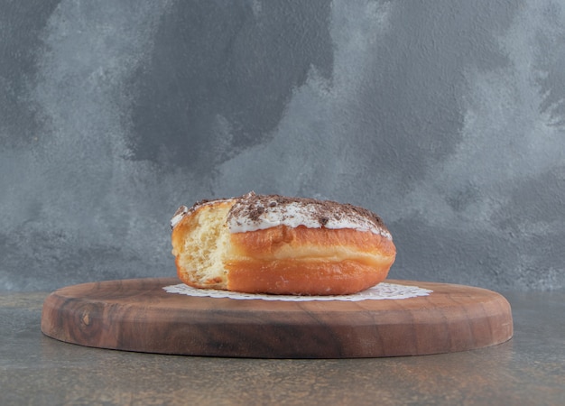 Free photo bitten donut on a wooden board