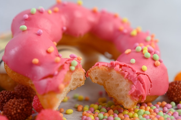 Bitten strawberry donut  decorated icing and sprinkling on the floor