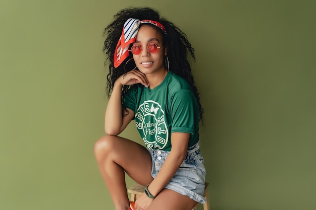 Foto gratuita donna afroamericana nera in t-shirt e pantaloncini alla moda hipster su verde