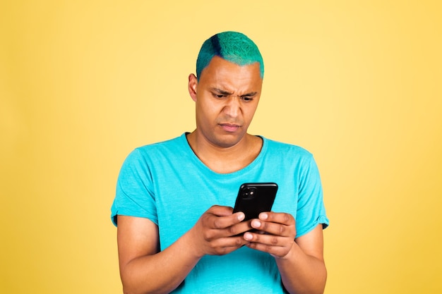 Black african man in casual on yellow wall with mobile phone looks with disgust, disgruntled face negative emotions