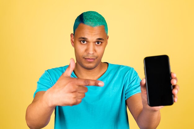 Black african man in casual on yellow wall with mobile phone positive happy point index finger on black empty screen