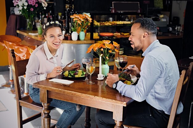 Black American male and female eating vegan food in a restaurant.