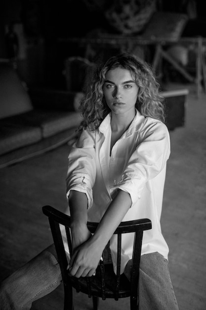 Бесплатное фото Черно-белый портрет красивой женщины, позирующей в помещении на стуле