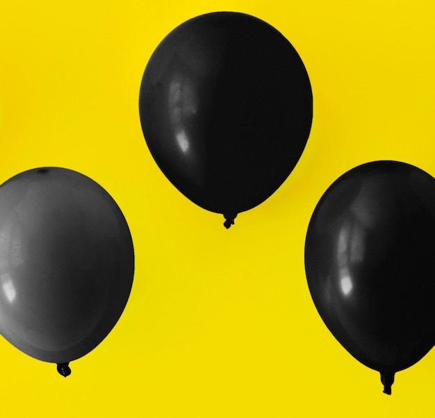 Foto gratuita palloncini neri su sfondo giallo