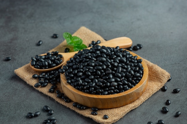 Free photo black bean in small wooden plate place on sack fabric