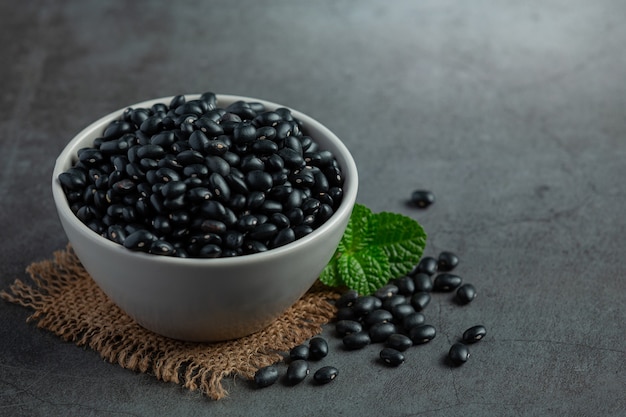 Free photo black beans in white small bowl place on dark floor