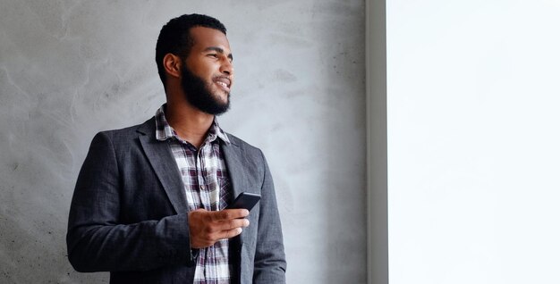 Black bearded male dressed in a fleece shirt and a jacket using a smart phone.