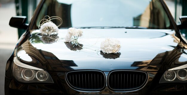 Free photo black bmw decorated with white wedding bouquets