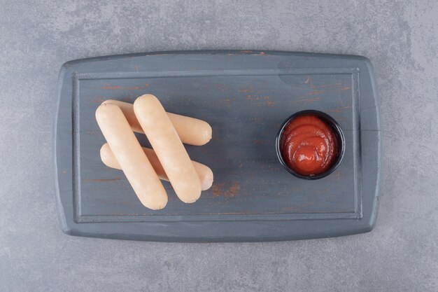 A black board of boiled sausages with ketchup 