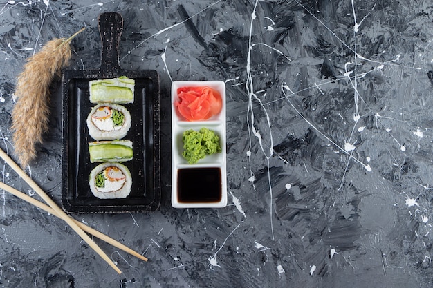 Black board with green dragon sushi rolls on marble background. 