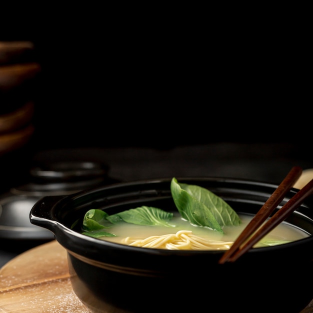 Black bowl with noodle soup on a black background