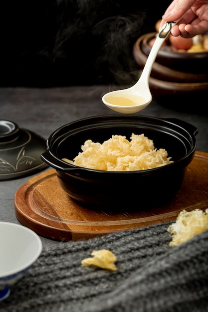 Black bowl with soup on a wooden plate